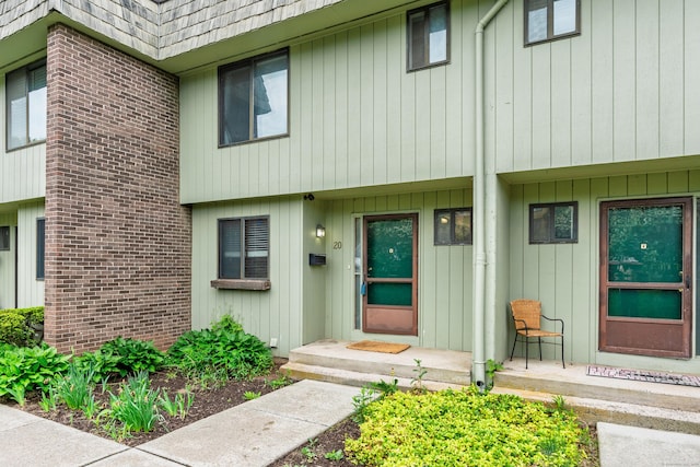 doorway to property with mansard roof and brick siding