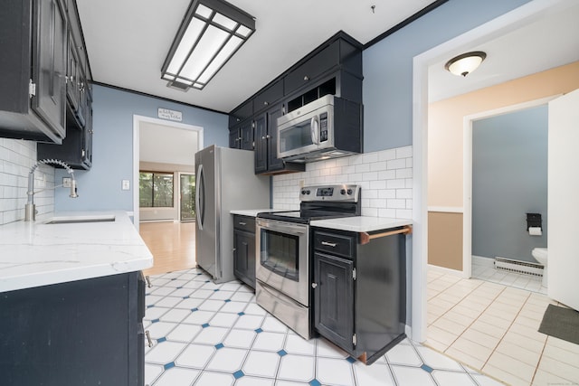 kitchen with appliances with stainless steel finishes, a sink, dark cabinets, and backsplash