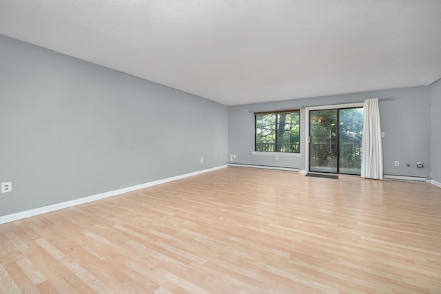 unfurnished room featuring baseboard heating, light wood-style floors, baseboards, and a baseboard heating unit