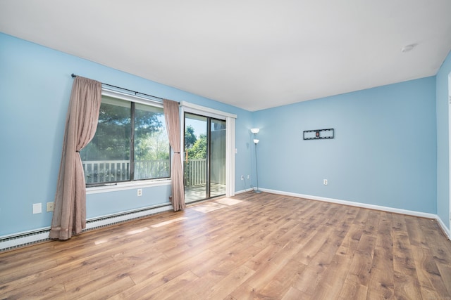 empty room with wood finished floors, baseboards, and baseboard heating