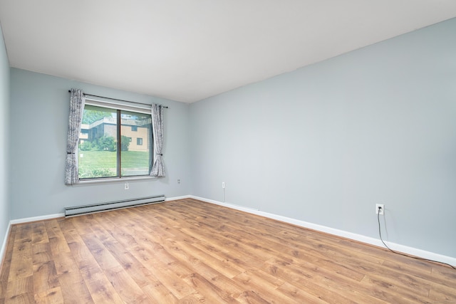 unfurnished room featuring a baseboard heating unit, wood finished floors, and baseboards