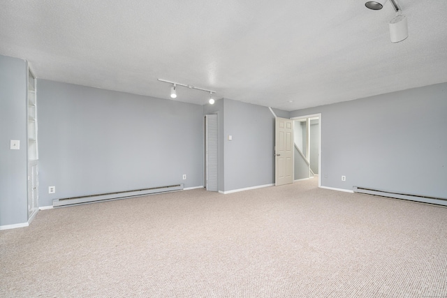 carpeted spare room featuring a baseboard radiator, track lighting, and baseboards