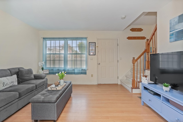 living room with light wood-style flooring, stairway, and baseboards