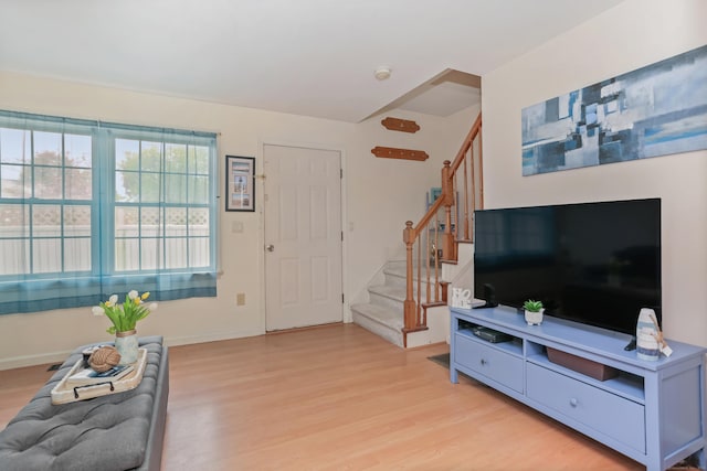 living room featuring stairs, light wood finished floors, and baseboards
