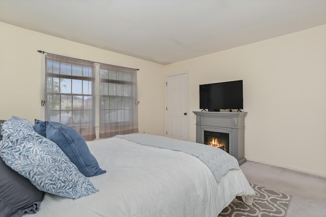 carpeted bedroom with a lit fireplace and baseboards