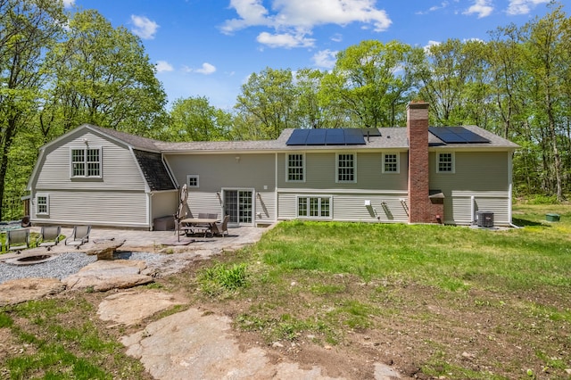 138 Flood Rd, Marlborough, CT 06447 - back of property with a patio, a chimney, roof mounted solar panels, and an outdoor fire pit