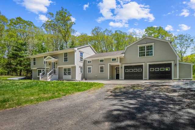 138 Flood Rd, Marlborough, CT 06447 - bi-level home with driveway, a front yard, a garage, a gambrel roof, and roof with shingles