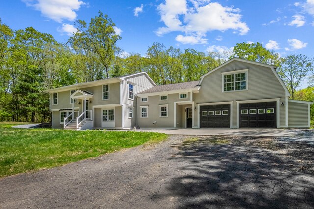 138 Flood Rd, Marlborough, CT 06447 - raised ranch featuring driveway, a front lawn, a garage, a gambrel roof, and a shingled roof