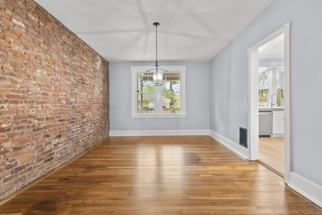 669 Third Ave, West Haven, CT 06516 - unfurnished dining area featuring a chandelier, light wood finished floors, brick wall, a sink, and baseboards