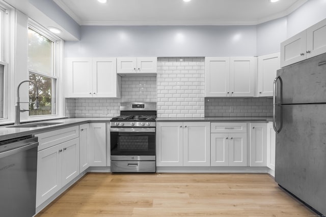669 Third Ave, West Haven, CT 06516 - kitchen featuring appliances with stainless steel finishes, crown molding, a sink, white cabinets, and backsplash