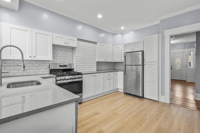 669 Third Ave, West Haven, CT 06516 - kitchen with appliances with stainless steel finishes, a sink, crown molding, white cabinets, and tasteful backsplash