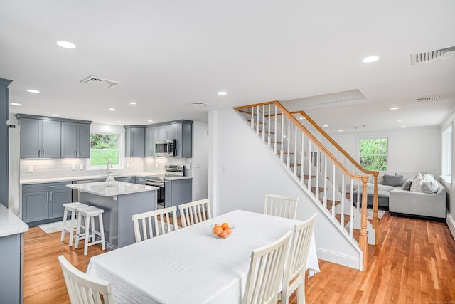 dining space featuring healthy amount of natural light, stairs, light wood-style flooring, and recessed lighting