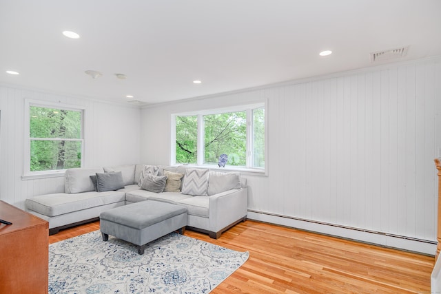 living room featuring a baseboard heating unit, healthy amount of natural light, wood finished floors, ornamental molding, and recessed lighting