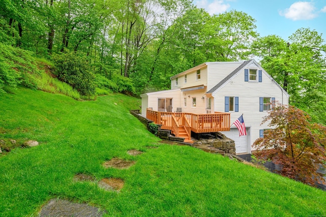 back of property with a deck, a garage, and a yard