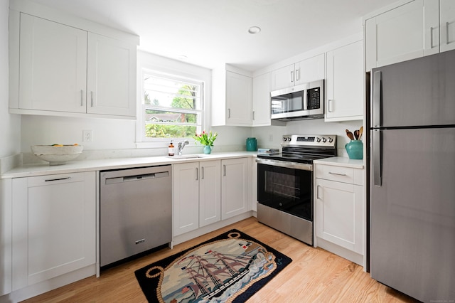14 Arnold Ln, Norwalk, CT 06853 - kitchen featuring appliances with stainless steel finishes, light wood-style flooring, a sink, white cabinetry, and recessed lighting