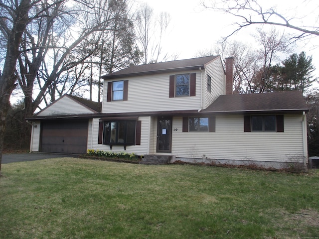 traditional home featuring a chimney, driveway, an attached garage, and a front yard