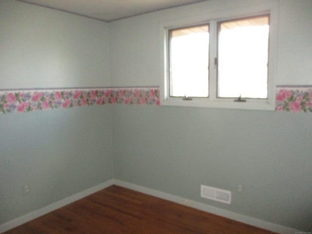 spare room featuring dark wood-style flooring and baseboards