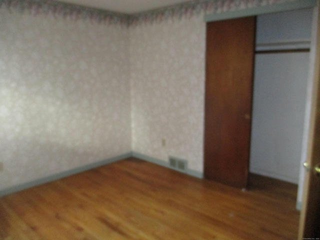 unfurnished bedroom with wood finished floors and a closet