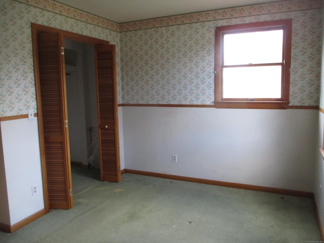 unfurnished bedroom featuring a closet, carpet floors, and wallpapered walls