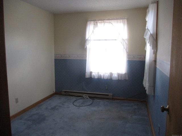 unfurnished room with a baseboard heating unit, carpet flooring, and baseboards