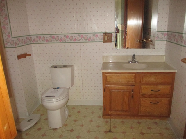 bathroom with wallpapered walls, vanity, toilet, and baseboards