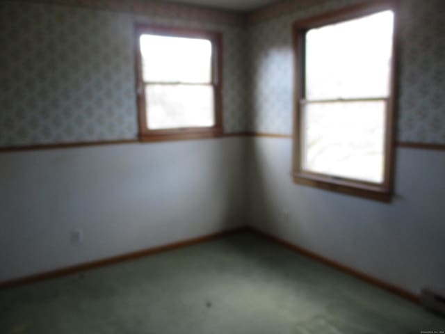 unfurnished room with healthy amount of natural light, carpet flooring, and wallpapered walls