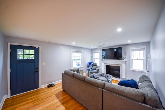 living area featuring a brick fireplace, light wood-type flooring, baseboards, recessed lighting, and healthy amount of natural light