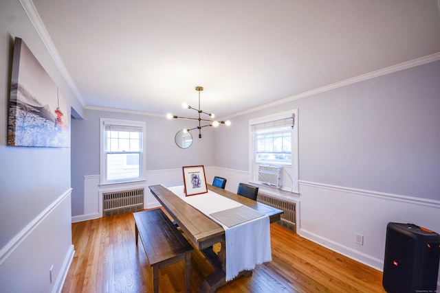 dining room featuring a chandelier, radiator heating unit, plenty of natural light, crown molding, and wood finished floors