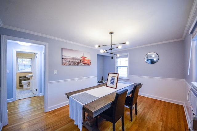 dining space featuring a chandelier, light wood-style floors, radiator heating unit, ornamental molding, and baseboards