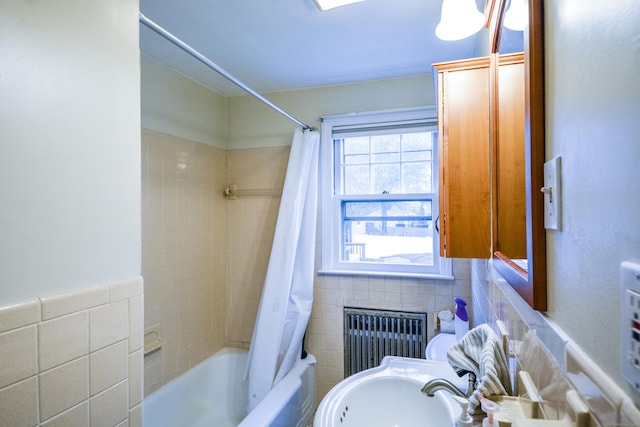 full bathroom featuring radiator, tile walls, shower / tub combo with curtain, and a sink