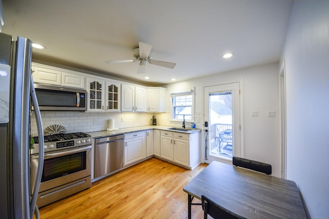kitchen with stainless steel appliances, a sink, tasteful backsplash, white cabinetry, and recessed lighting