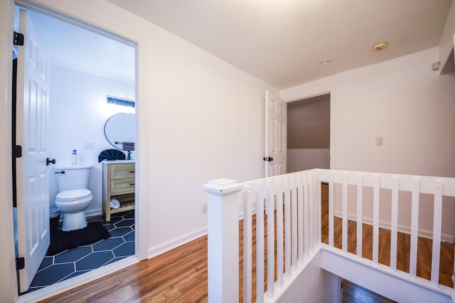 hall featuring an upstairs landing and wood finished floors