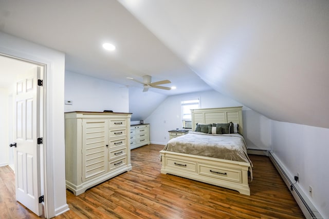 bedroom with wood finished floors, lofted ceiling, a baseboard heating unit, baseboards, and a ceiling fan