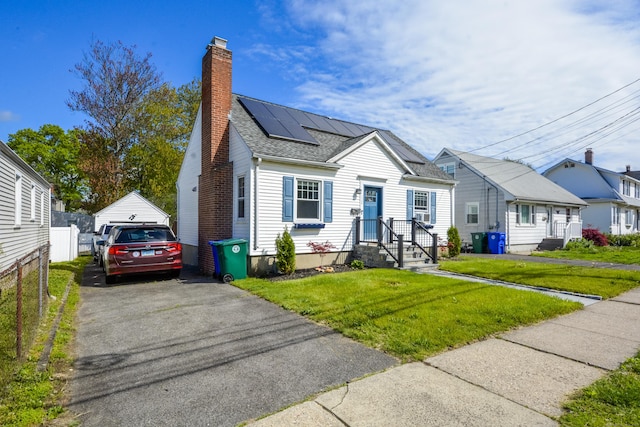 view of front of house featuring a chimney, solar panels, roof with shingles, and a detached garage