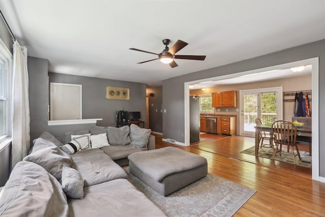 living area featuring ceiling fan, light wood-style floors, and baseboards