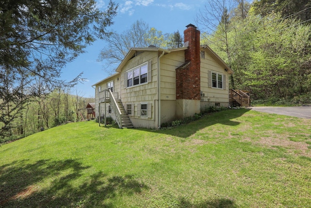 view of property exterior with stairway, a chimney, and a yard
