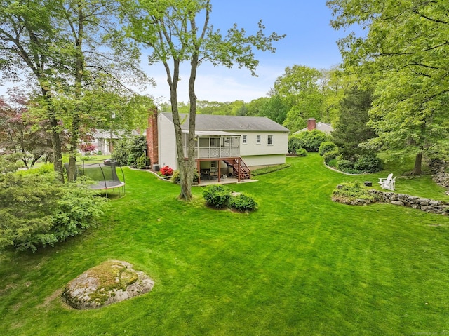 9 Cindy Ln, Norwalk, CT 06851 - back of property with a trampoline, stairs, a wooden deck, a chimney, and a yard