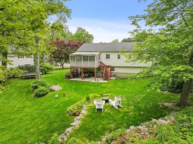 9 Cindy Ln, Norwalk, CT 06851 - back of property with a sunroom, a trampoline, a patio, a lawn, and stairs
