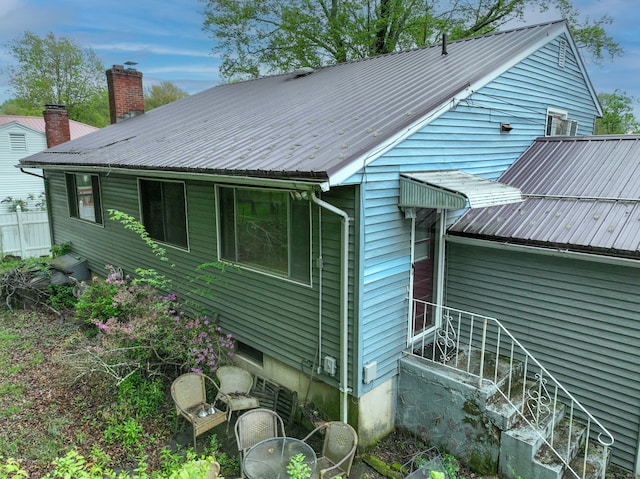 back of property featuring metal roof and a chimney