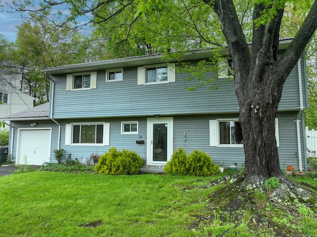 colonial home with an attached garage, a front lawn, and driveway