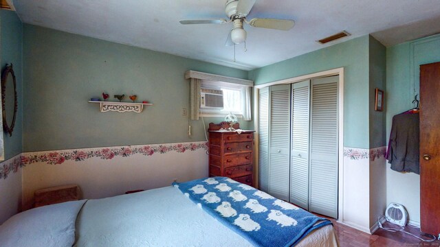 bedroom with a closet, a wall mounted air conditioner, a ceiling fan, and wainscoting