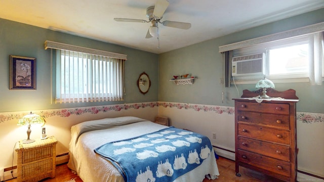 bedroom with baseboard heating, wood finished floors, a ceiling fan, and wainscoting