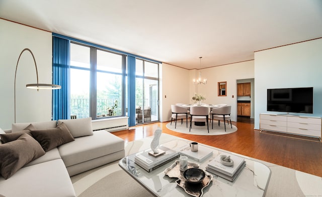 living area featuring a chandelier, wood finished floors, a baseboard heating unit, and expansive windows