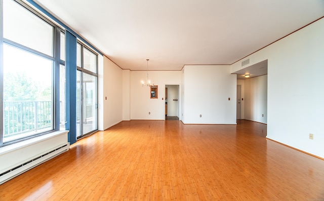 unfurnished room with baseboard heating, a chandelier, and light wood finished floors
