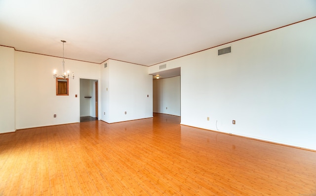 empty room featuring a chandelier and wood finished floors