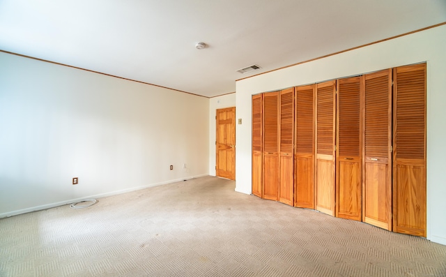 unfurnished bedroom featuring light carpet, baseboards, and a closet