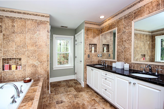 56 Grouse Ln, Woodbridge, CT 06525 - bathroom with baseboards, double vanity, tiled tub, tile walls, and stone finish floors