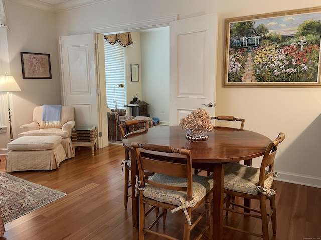 dining room featuring a chandelier, crown molding, wood finished floors, and baseboards