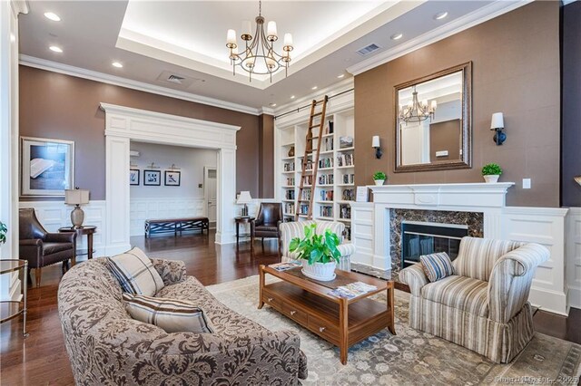 living room with a chandelier, ornamental molding, wood finished floors, built in features, and recessed lighting