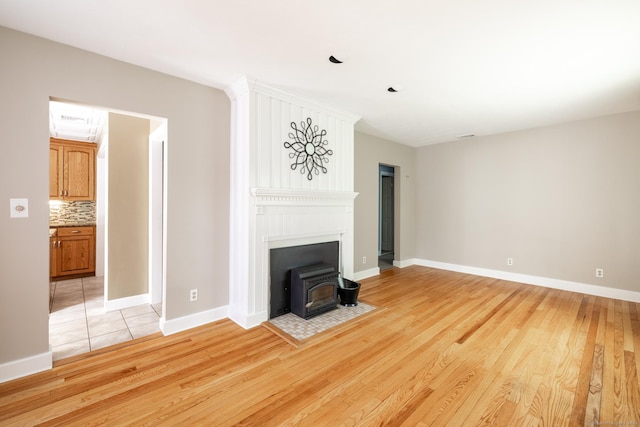 153 Mountain Rd, Cheshire, CT 06410 - unfurnished living room featuring a wood stove, light wood-style flooring, and baseboards